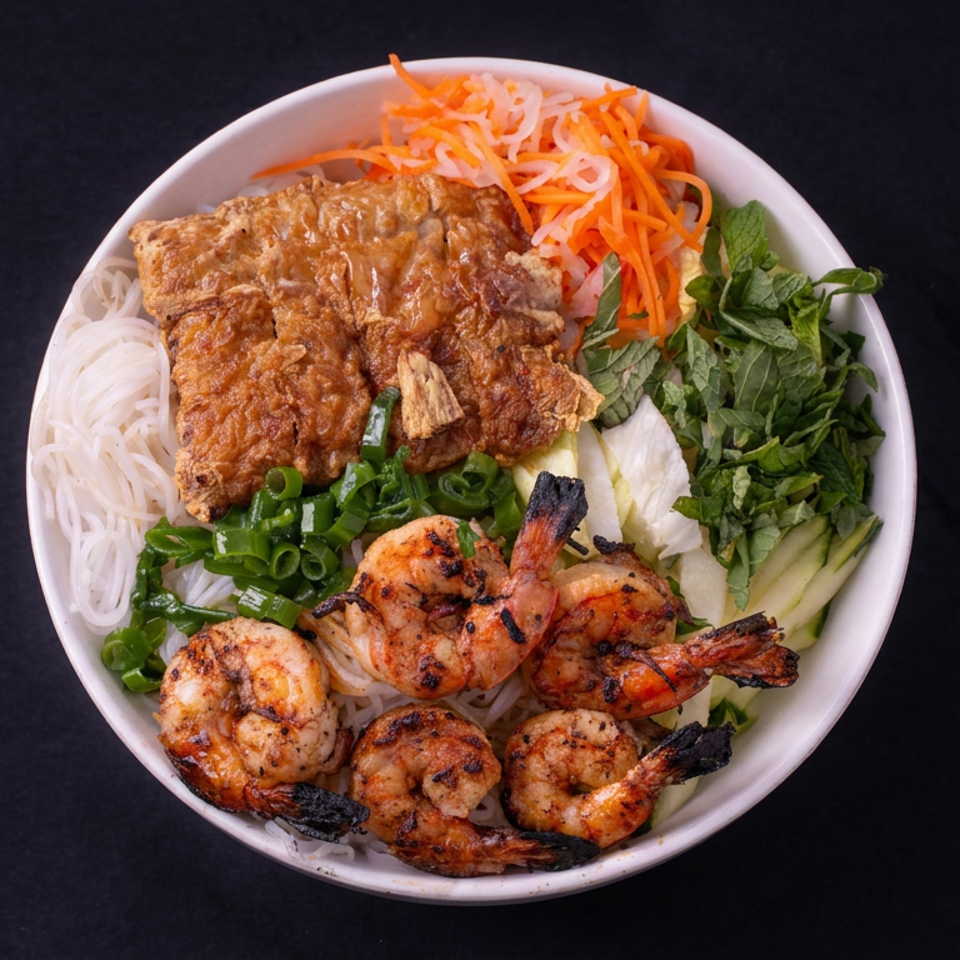 Vietnamese rice noodle bowl topped with grilled shrimp, crispy pork, pickled carrots, herbs, cucumber, and green onions.